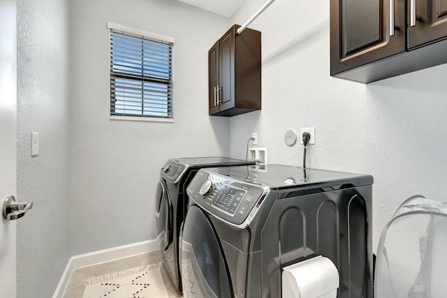 clothes washing area with cabinets, light tile patterned floors, and washing machine and clothes dryer