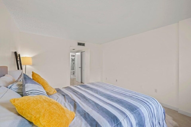 bedroom featuring light colored carpet and ensuite bath