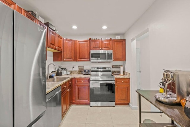 kitchen with appliances with stainless steel finishes, light stone countertops, sink, and light tile patterned floors