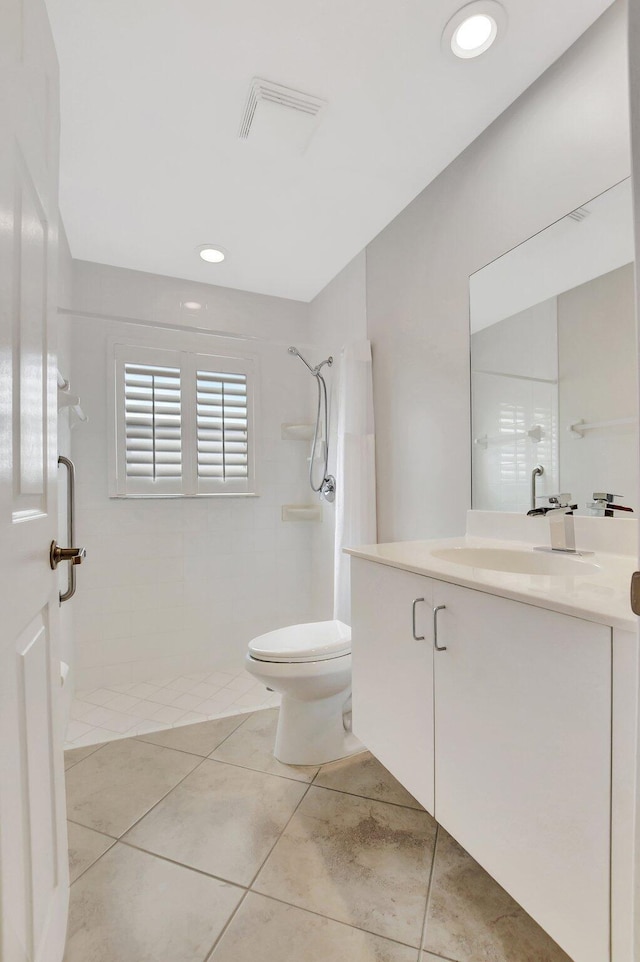 bathroom featuring vanity, toilet, and a tile shower