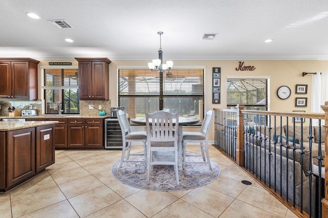 kitchen featuring a notable chandelier, a wealth of natural light, wine cooler, and backsplash