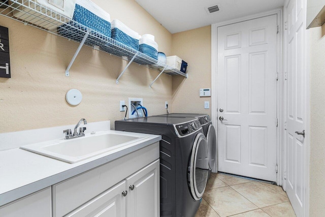 laundry room featuring light tile patterned flooring, cabinets, sink, and washer and dryer