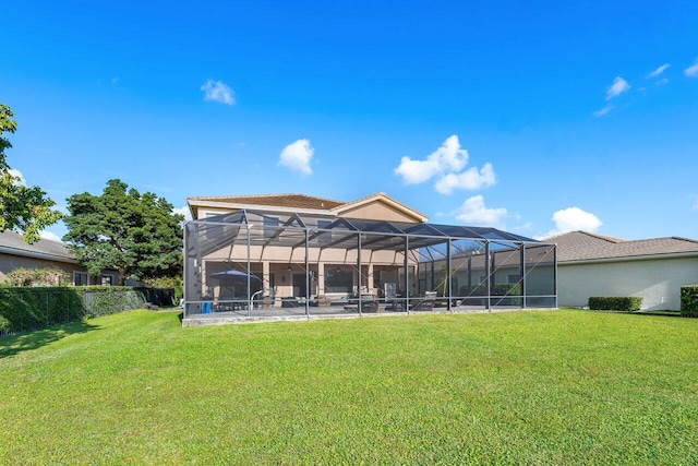 rear view of house featuring a lawn and glass enclosure