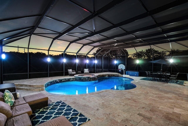 pool at dusk with an in ground hot tub, a patio, and glass enclosure