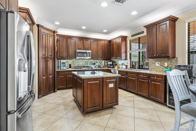 kitchen featuring stainless steel appliances, light stone countertops, a kitchen island, and light tile patterned floors