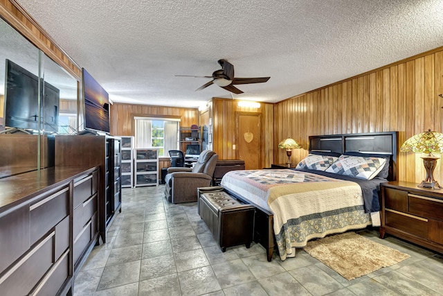 bedroom featuring ceiling fan, wooden walls, and a textured ceiling