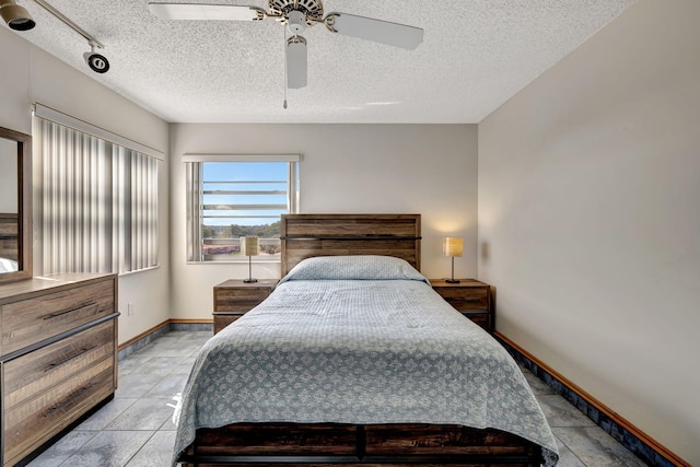 bedroom featuring ceiling fan, light tile patterned floors, and a textured ceiling