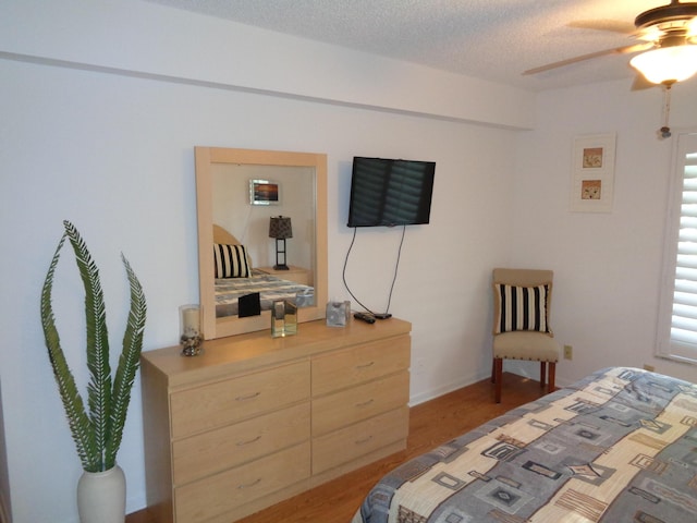 bedroom featuring ceiling fan, hardwood / wood-style floors, and a textured ceiling