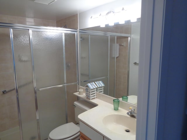 bathroom with vanity, a shower with shower door, and toilet