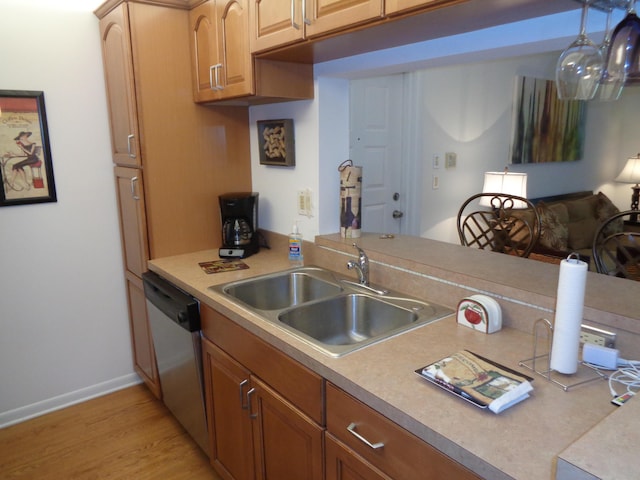 kitchen featuring sink, hanging light fixtures, dishwasher, and light wood-type flooring