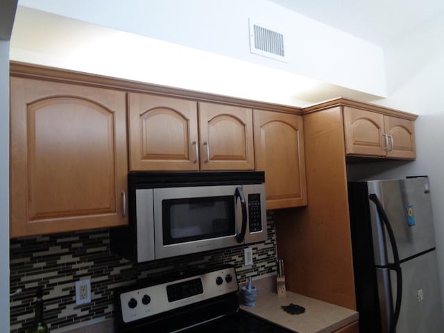 kitchen featuring appliances with stainless steel finishes, backsplash, and light brown cabinetry