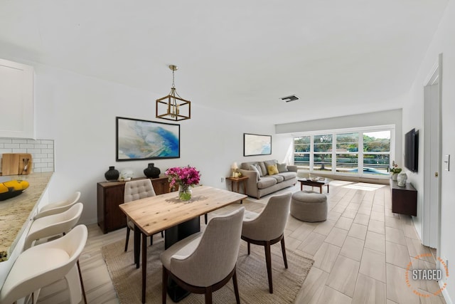 dining space with light wood-style flooring, visible vents, and an inviting chandelier