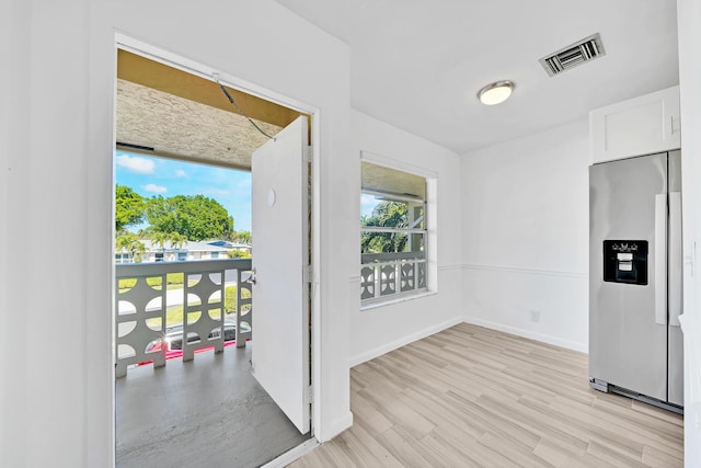 spare room featuring light wood-style floors, baseboards, and visible vents