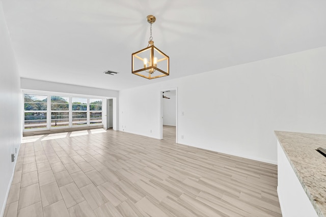 unfurnished living room with light wood finished floors, visible vents, and an inviting chandelier