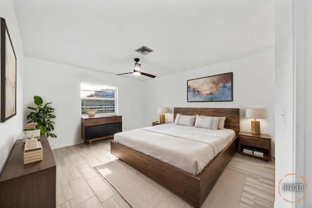 bedroom with light wood finished floors, visible vents, and a ceiling fan