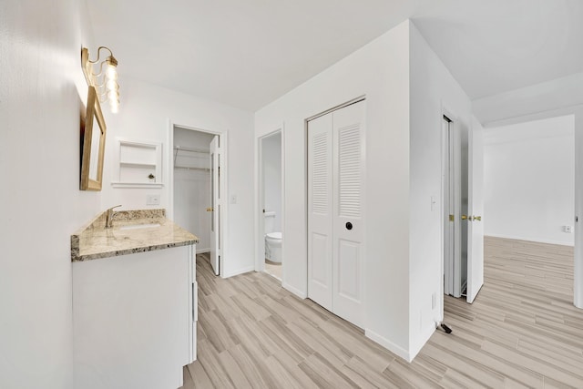 hall with baseboards, a sink, and light wood-style floors