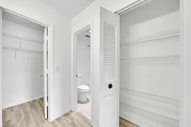 interior space with wood finished floors, toilet, and baseboards