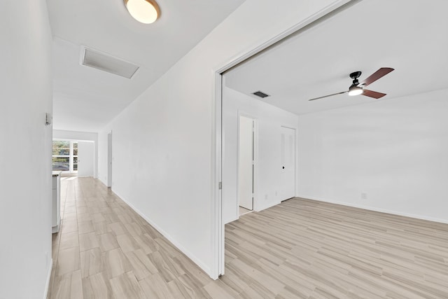 hallway with light wood-style floors, baseboards, and visible vents