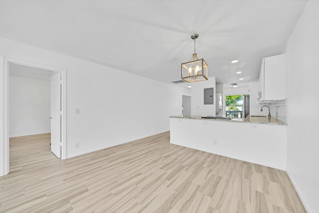 kitchen with white cabinets, decorative backsplash, light stone counters, a peninsula, and pendant lighting