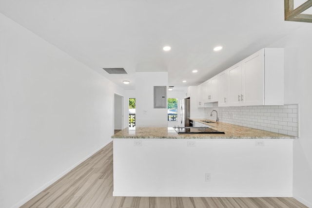 kitchen featuring white cabinets, a sink, a peninsula, and stainless steel refrigerator