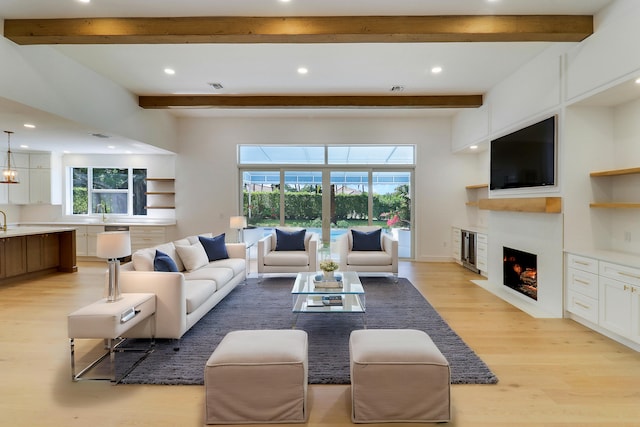 living room featuring beamed ceiling, sink, and light hardwood / wood-style flooring