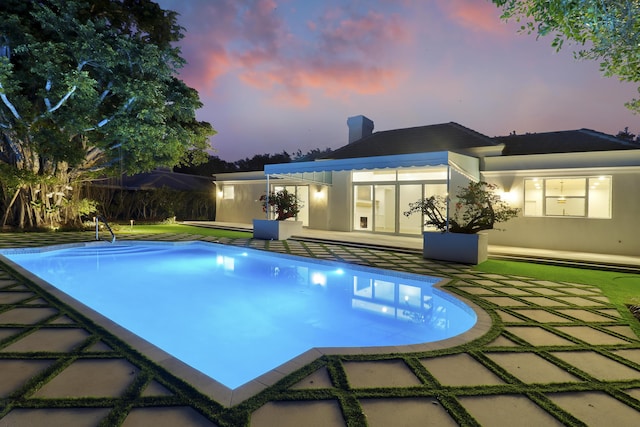 pool at dusk with a patio area