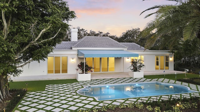 back house at dusk featuring a patio