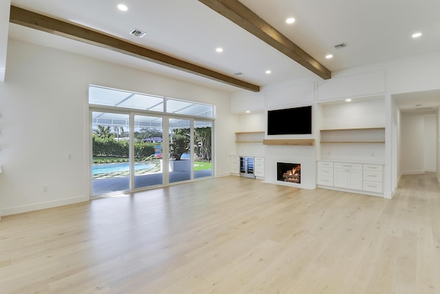 unfurnished living room with beamed ceiling and light hardwood / wood-style flooring