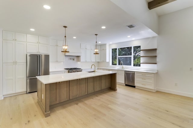 kitchen featuring sink, light hardwood / wood-style flooring, appliances with stainless steel finishes, white cabinetry, and an island with sink