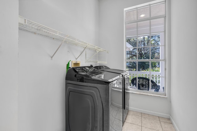 laundry area featuring laundry area, washing machine and dryer, baseboards, and light tile patterned flooring