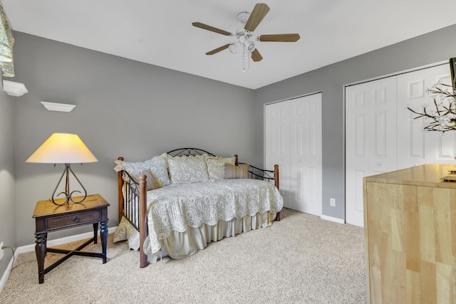 carpeted bedroom with a ceiling fan, baseboards, and two closets