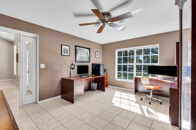 office area with light tile patterned flooring, a ceiling fan, and baseboards