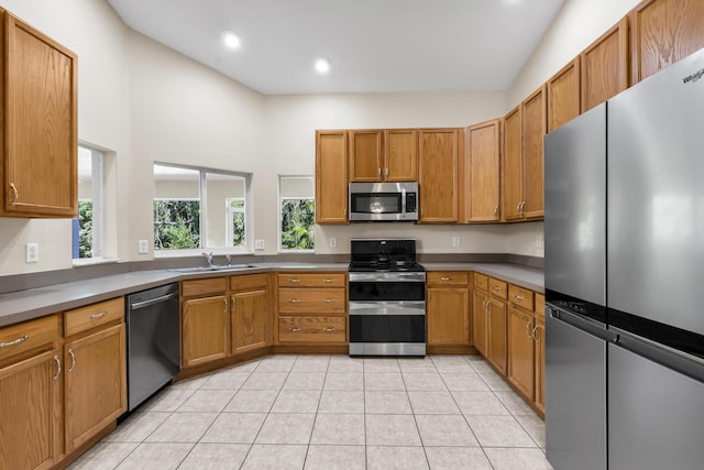 kitchen with light tile patterned floors, recessed lighting, a sink, appliances with stainless steel finishes, and brown cabinetry