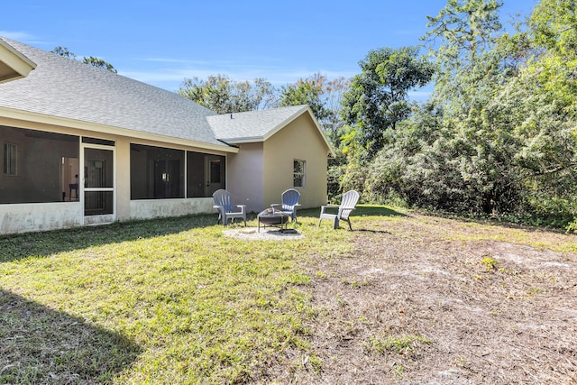 view of yard featuring a sunroom and a fire pit