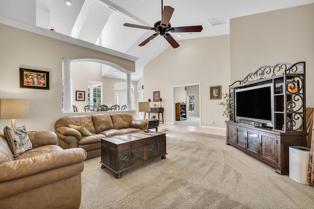 living room with decorative columns, ceiling fan, light colored carpet, and high vaulted ceiling