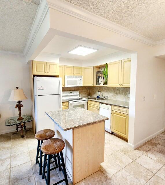 kitchen with sink, white appliances, ornamental molding, light brown cabinetry, and decorative backsplash