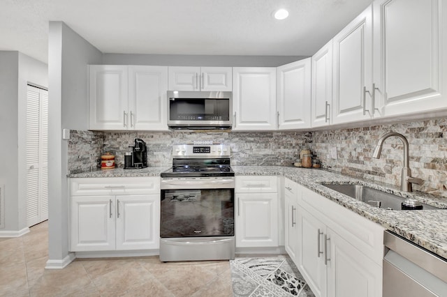 kitchen with white cabinetry, appliances with stainless steel finishes, and light stone countertops