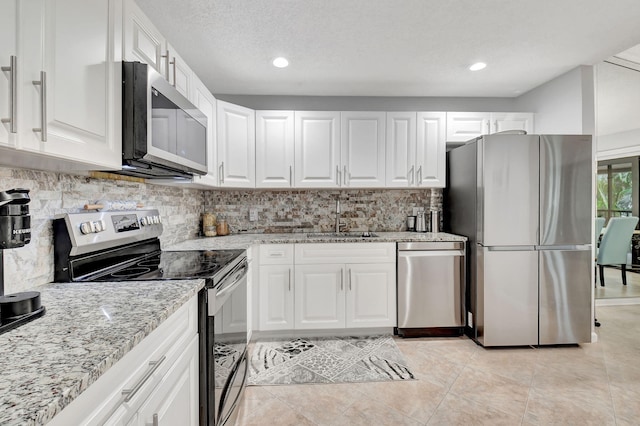 kitchen featuring sink, white cabinetry, tasteful backsplash, light stone counters, and stainless steel appliances