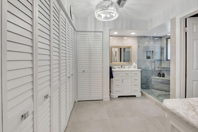 bathroom featuring an inviting chandelier, vanity, a shower with door, and tile patterned flooring