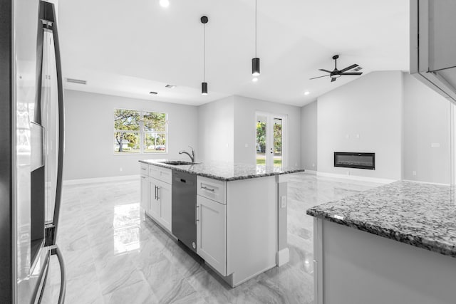 kitchen with sink, stone countertops, decorative light fixtures, a center island with sink, and appliances with stainless steel finishes