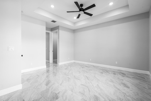 empty room featuring a tray ceiling and ceiling fan