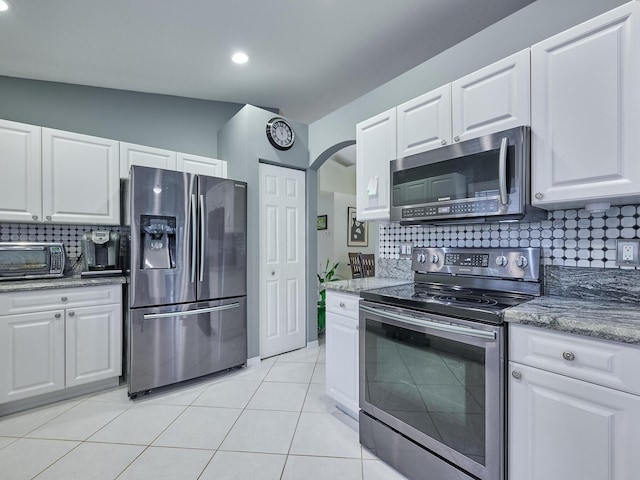 kitchen with stainless steel appliances, tasteful backsplash, light tile patterned floors, and white cabinets