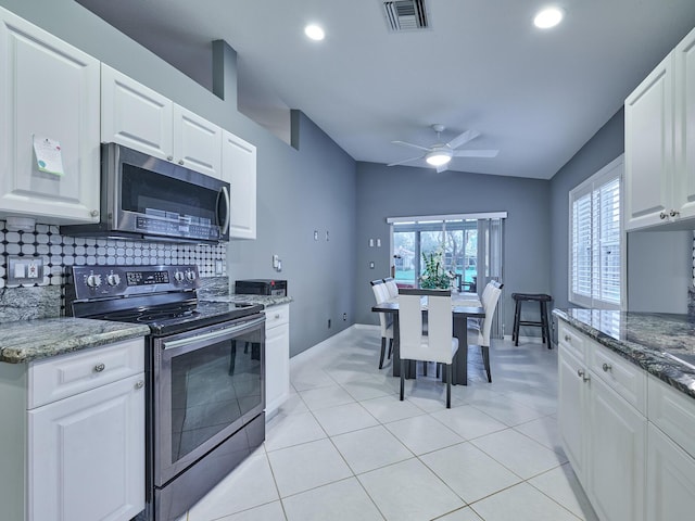 kitchen with dark stone countertops, appliances with stainless steel finishes, tasteful backsplash, and white cabinets