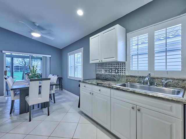 kitchen with lofted ceiling, sink, white cabinets, backsplash, and light tile patterned floors