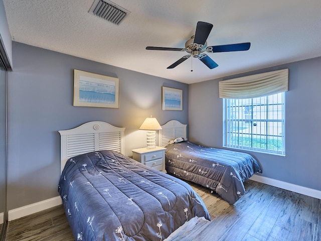 bedroom featuring ceiling fan, dark hardwood / wood-style floors, and a textured ceiling