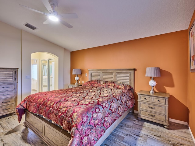 bedroom featuring hardwood / wood-style flooring, ceiling fan, lofted ceiling, and ensuite bath