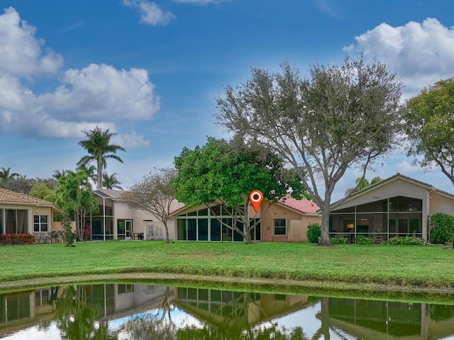 rear view of property with a water view and a yard