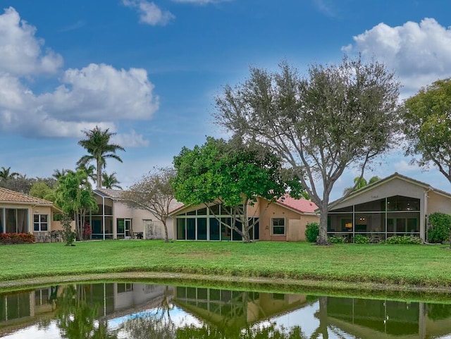 rear view of house with a lawn and a water view