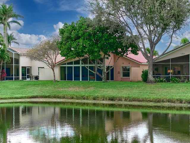 back of property with a water view and a lawn