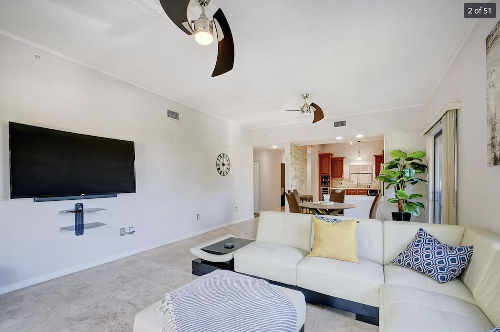 living room with ceiling fan and ornamental molding